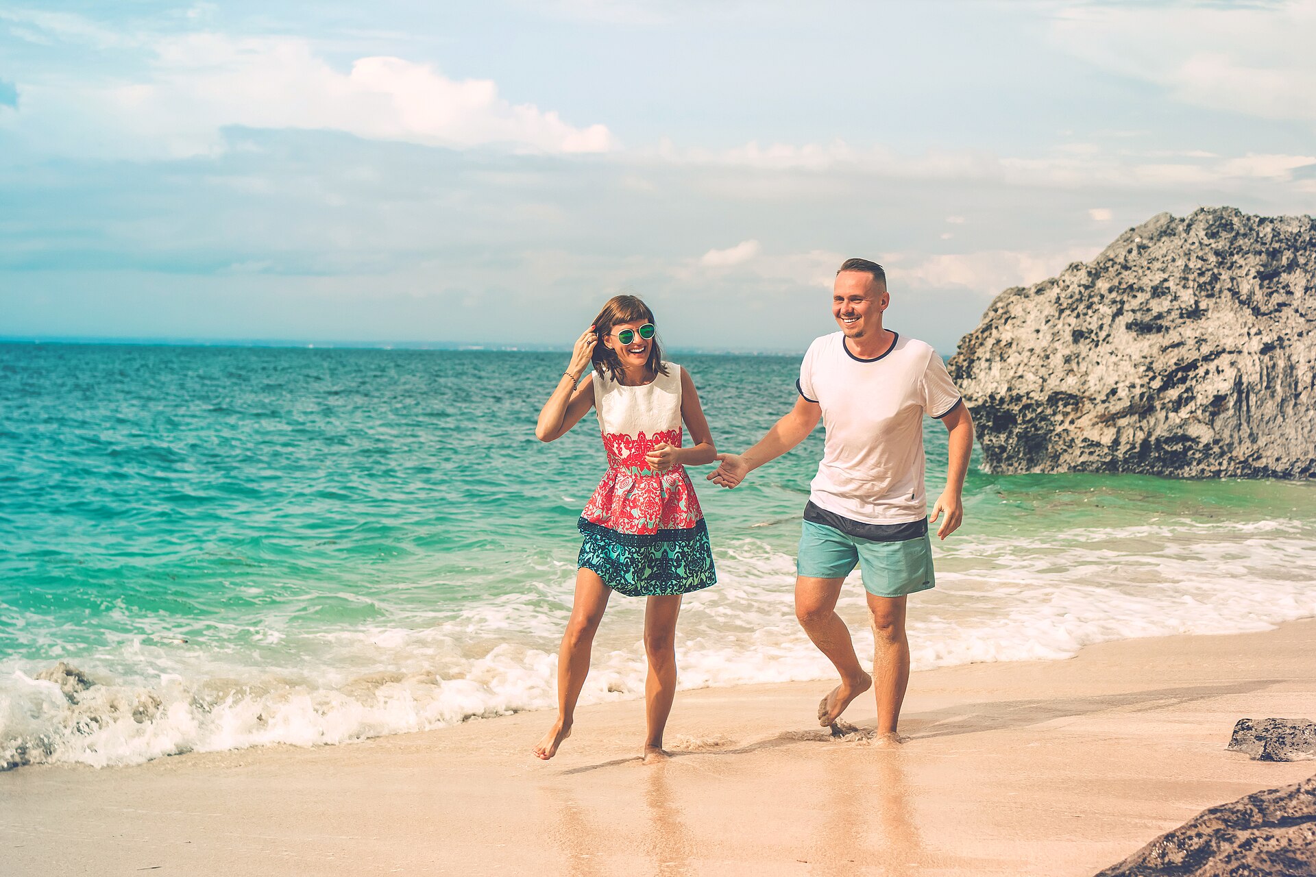 Happy young honeymoon couple having fun on the beach. Ocean, tropical vacation on Bali island.